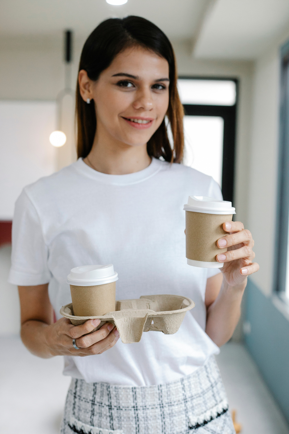 Cheerful female with takeaway coffee in office